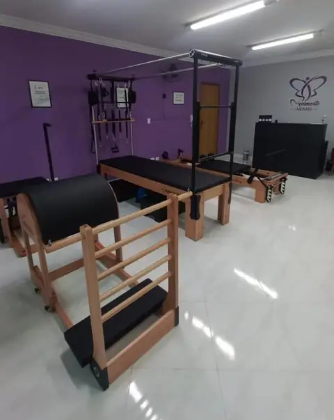 Sala do estúdio com aparelhos de Pilates e parede lilás